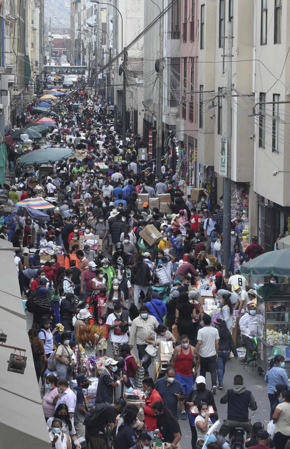 Pedestrians wearing face masks amid the COVID-19 pandemic walk in the Mesa Redonda Market, a popular spot for Christmas shopping in Lima, Peru, Friday, Dec. 18, 2020. Peru's Health Ministry has announced on Tuesday, Dec. 22, that it has surpassed 1 million confirmed cases of the new coronavirus. (AP Photo/Martin Mejia, File)