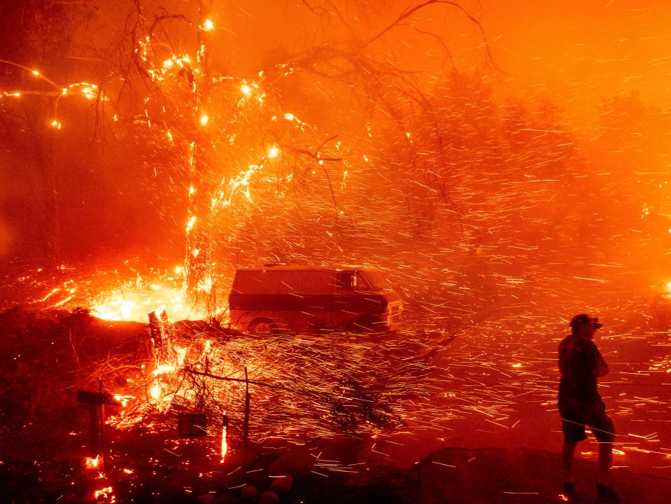 <p>Bruce McDougal prepares to defend his home as the Bond Fire burns though the Silverado community in Orange County, California, on 3 December 2020</p> (Noah Berger/AP)