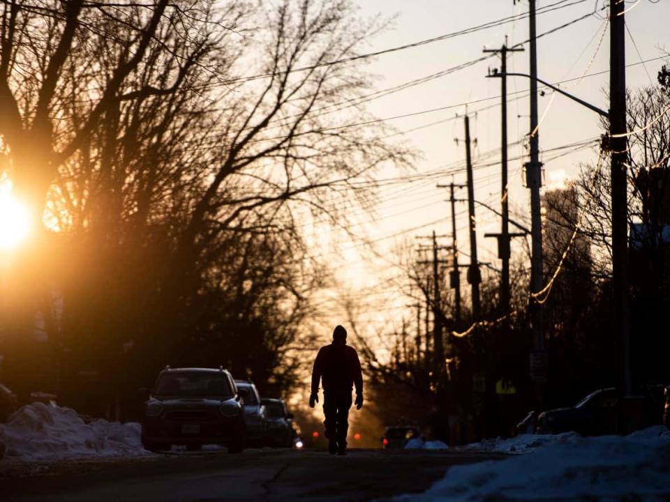 A person walks through the Glebe as the sun sets Saturday, during the Omicron wave of the COVID-19 pandemic. (Justin Tang/The Canadian Press - image credit)