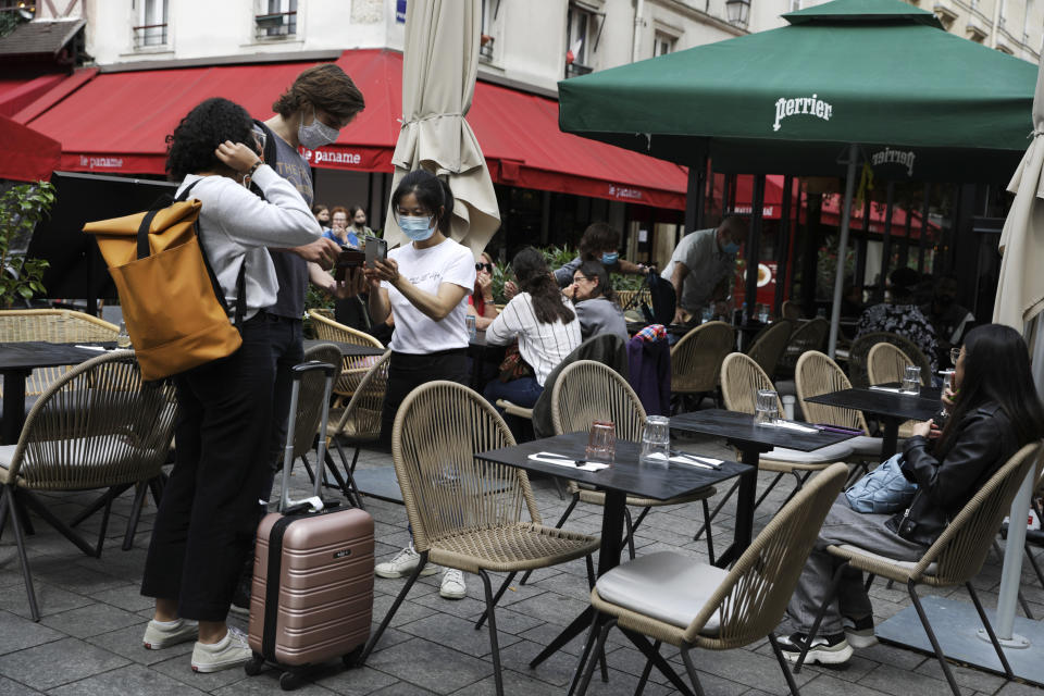 FILE - In this Aug. 9, 2021, file photo, an employee checks a clients' health pass at a restaurant in Paris. In the European Union, officials in many places are requiring people to show proof of vaccination, a negative test or recent recovery from COVID-19 to participate in everyday activities — even sometimes to go to work. Struggling to boost its paltry vaccination rates in the early summer, France was the first major EU nation to start using such passes. (AP Photo/Adrienne Surprenant, File)