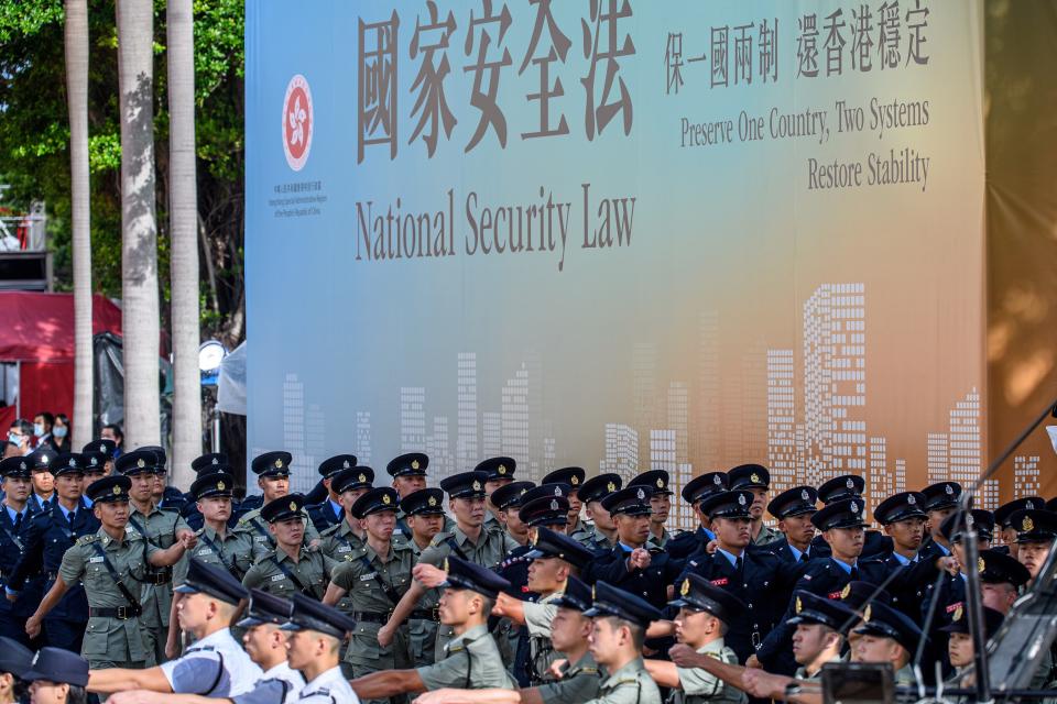 Attendees from various forces march next to a banner supporting the new national security law at the end of a flag-raising ceremony to mark the 23rd anniversary of Hong Kong's handover from Britain in Hong Kong on July 1, 2020. - Hong Kong marked the 23rd anniversary of its handover to China on July 1 under the glare of a new national security law imposed by Beijing, with protests banned and the city's cherished freedoms looking increasingly fragile. (Photo by Anthony WALLACE / AFP) (Photo by ANTHONY WALLACE/AFP via Getty Images)