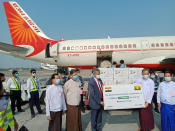 In this photo released by the Indian Embassy in Myanmar, Indian Ambassador to India Saurabh Kumar, third from right, holds a sign with Prof. Zaw Than Htun, director-general of Medical Research Department under Myanmar's Health and Sports Ministry, in front of boxes of the Covishield vaccine delivered from India at the Yangon International Airport Friday, Jan. 22, 2021 in Yangon, Myanmar. Myanmar on Friday received its first shipment of COVID-19 vaccine, a government-to-government gift of 1.5 million doses from India. (Indian Embassy in Myanmar via AP)