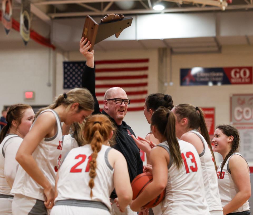 Bedford girls basketball coach Bill Ryan raises the championship trophy after Bedford beat Trenton 74-33 in the finals of the Division 1 District at Bedford on Friday, March 8, 2024.