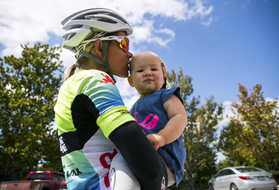 In this undated photo, three-time Ironman world champion Mirinda Carfrae kisses her 1-year-old daughter, Isabelle, before heading out on a training ride near Lawrence, Kan. Carfrae and her husband, Tim O'Donnell, are preparing for next month's Ironman world championships in Kona, Hawaii. (Talbot Cox via AP)