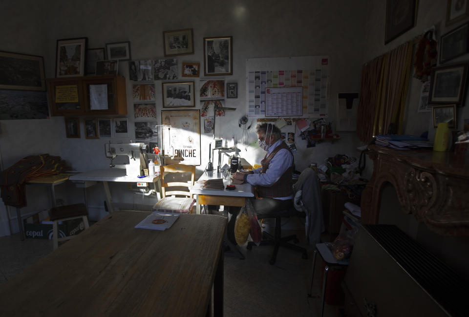 Tailor Karl Kersten sews pieces of Gilles de Binche costumes at his atelier in Binche, Belgium, Thursday, Feb. 11, 2021. The economic impact of the cancellation of this years carnival due to COVID-19 will be difficult for local craftspersons who rely on the income. Kersten, a fourth-generation tailor of Gilles de Binche costumes, spends all year preparing for the event and rents about 1,000 costumes. In normal life, the small town of Binche would be bursting with excitement as craftsmen put the finishing touches to vibrant costumes, but in 2021 the COVID-19 regulations have forced the carnival to be cancelled. (AP Photo/Virginia Mayo)