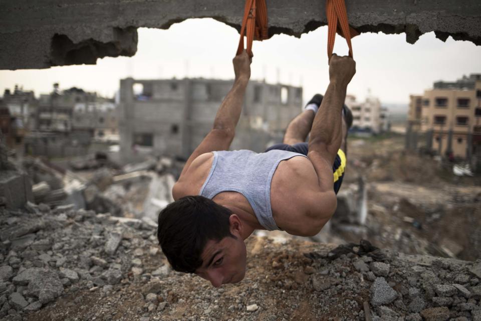 Palestinian Mahmoud Nasman, of team Bar Palestine, suspends during street exercises amid the destruction in Gaza City on August 3, 2015. Street workout, that is still new to Gaza, is a growing sport across the world with annual competitions and events.