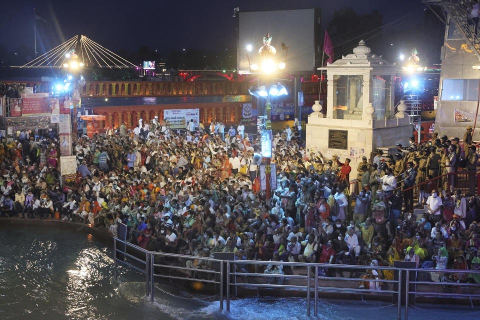 Devotees sit and pray in the evening on the ghats of the Ganges River during Kumbh Mela, or pitcher festival, one of the most sacred pilgrimages in Hinduism, in Haridwar, northern state of Uttarakhand, India, Monday, April 12, 2021. Tens of thousands of Hindu devotees gathered by the Ganges River for special prayers Monday, many of them flouting social distancing practices as the coronavirus spreads in India with record speed. (AP Photo/Karma Sonam)