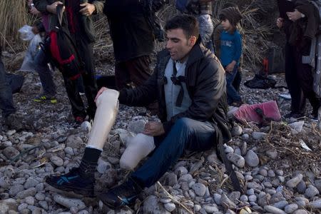 An Afghan refugee prepares to put on his prosthetic leg moments after arriving on an overcrowded dinghy on the Greek island of Lesbos, after crossing a part of the Aegean Sea from the Turkish coast, October 8, 2015. Refugee and migrant arrivals to Greece this year will soon reach 400,000, according to the UN Refugee Agency (UNHCR). REUTERS/Dimitris Michalakis TPX IMAGES OF THE DAY - RTS3ML4