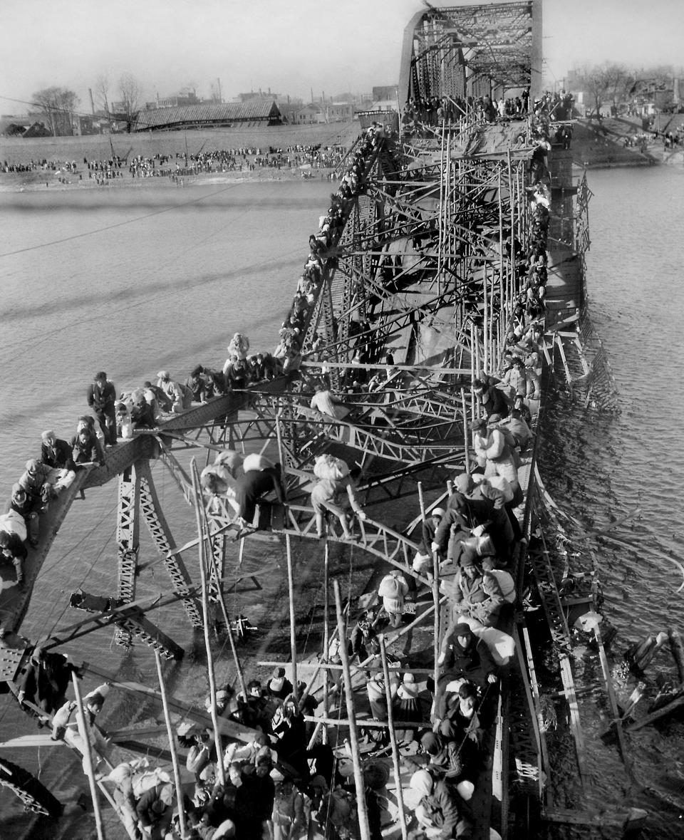 FILE - Residents from Pyongyang, North Korea, and refugees from other areas crawl over shattered girders of the city's bridge to flee south across the Taedong River and escape the advance of Chinese Communist troops, Dec. 4, 1950. The Chinese entered the Korean War as allies of North Korea, while U.S. troops battled in support of South Korea. The fighting ended in 1953 with a military demarcation line set near the 38th parallel where it started in 1950, and Korea remains divided today. (AP Photo/Max Desfor, File)