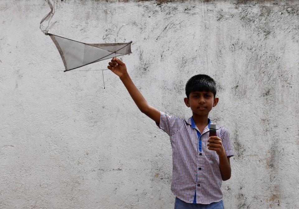 Oshada Fernando, 11, poses with the kite that his uncle made for him (Reuters)