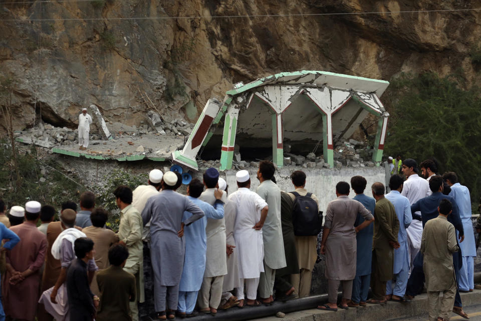 People Stand and watch the damaged mosque after a suicide bomber attack inside a roadside mosque in the Khyber district in Khyber Pakhtunkhwa province, of Pakistan, Tuesday, July 25, 2023. A suicide bomber blew himself up inside a roadside mosque when a police officer tried to arrest him after a chase in northwestern Pakistan near the Afghan border on Tuesday, killing the officer, police said. (AP Photo/Muhammad Sajjad)