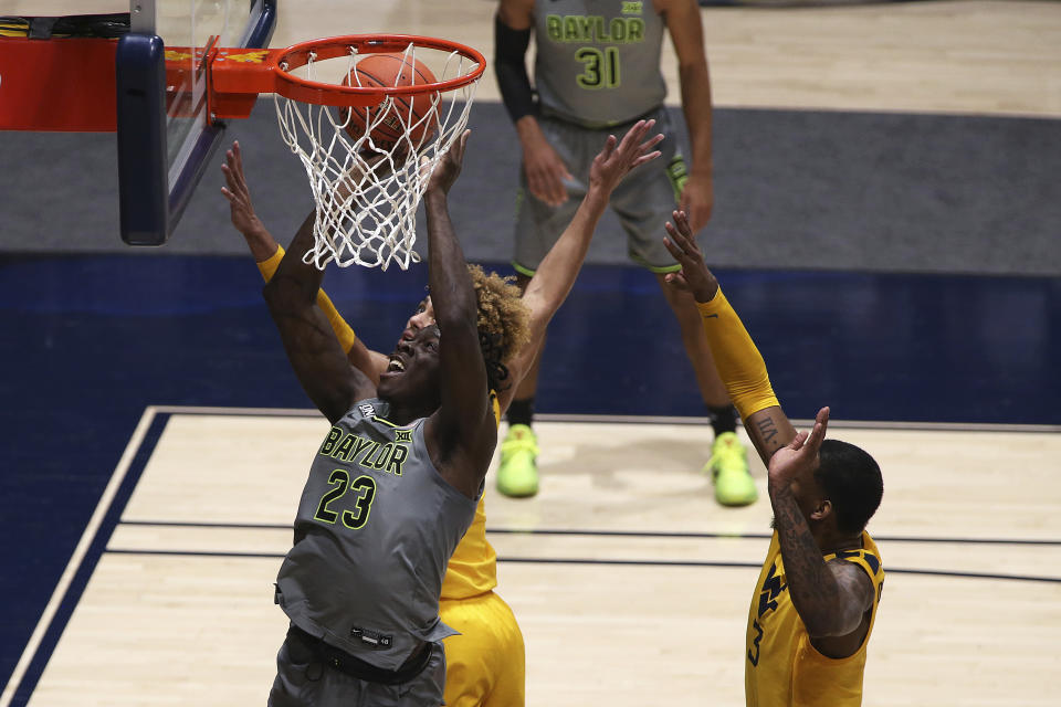 Baylor forward Jonathan Tchamwa Tchatchoua (23) shoots as West Virginia forwards Emmitt Matthews Jr. (11) and Gabe Osabuohien (3) defend during the second half of an NCAA college basketball game Tuesday, March 2, 2021, in Morgantown, W.Va. (AP Photo/Kathleen Batten)