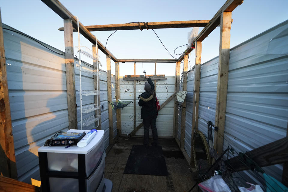 CORRECTS SPELLING TO CRISTIN, INSTEAD OF CRISTEN - Cristin Trahan looks at a new shower head and water heater, where she will take a hot shower for the first time since Hurricanes Laura and Delta, in a makeshift shower stall, where she now lives in a tent with her husband where their destroyed home once stood, in Lake Charles, La., Friday, Dec. 4, 2020. (AP Photo/Gerald Herbert)