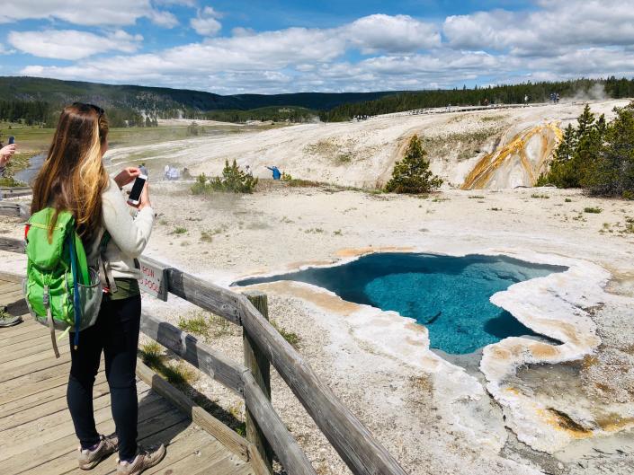 A woman takes photos of Blue Star spring near Old Faithful Upper Geyser Basin in Yellowstone National Park. (Photo: DANIEL SLIM via Getty Images)