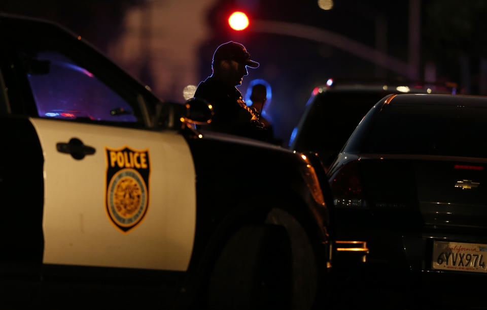 A law enforcement officer mans a barricade near a home that authorities have surrounded where an armed suspect has taken refuge after shooting a Sacramento police officer, Wednesday, June 19, 2019, in Sacramento, Calif. (AP Photo/Rich Pedroncelli)