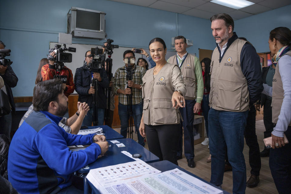 OAS electoral observers tour a polling station during the snap presidential election in Quito, Ecuador, Sunday, Aug. 20, 2023. The election was called after President Guillermo Lasso dissolved the National Assembly by decree in May to avoid being impeached. (AP Photo/Carlos Noriega)