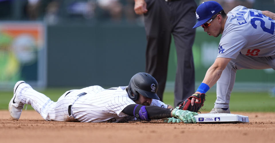 Colorado Rockies' Jake Cave, left, slides safely into second base with a double as Los Angeles Dodgers shortstop Tommy Edman, right, applies a late tag in the fifth inning of a baseball game Sunday, Sept. 29, 2024, in Denver. (AP Photo/David Zalubowski)