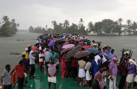 Volunteers use umbrellas to protect from rain as they cross Pampa river to reach to flood-affected areas to clean houses and public places following floods in Kuttanad in Alappuzha district in Kerala, August 28, 2018. REUTERS/Sivaram V