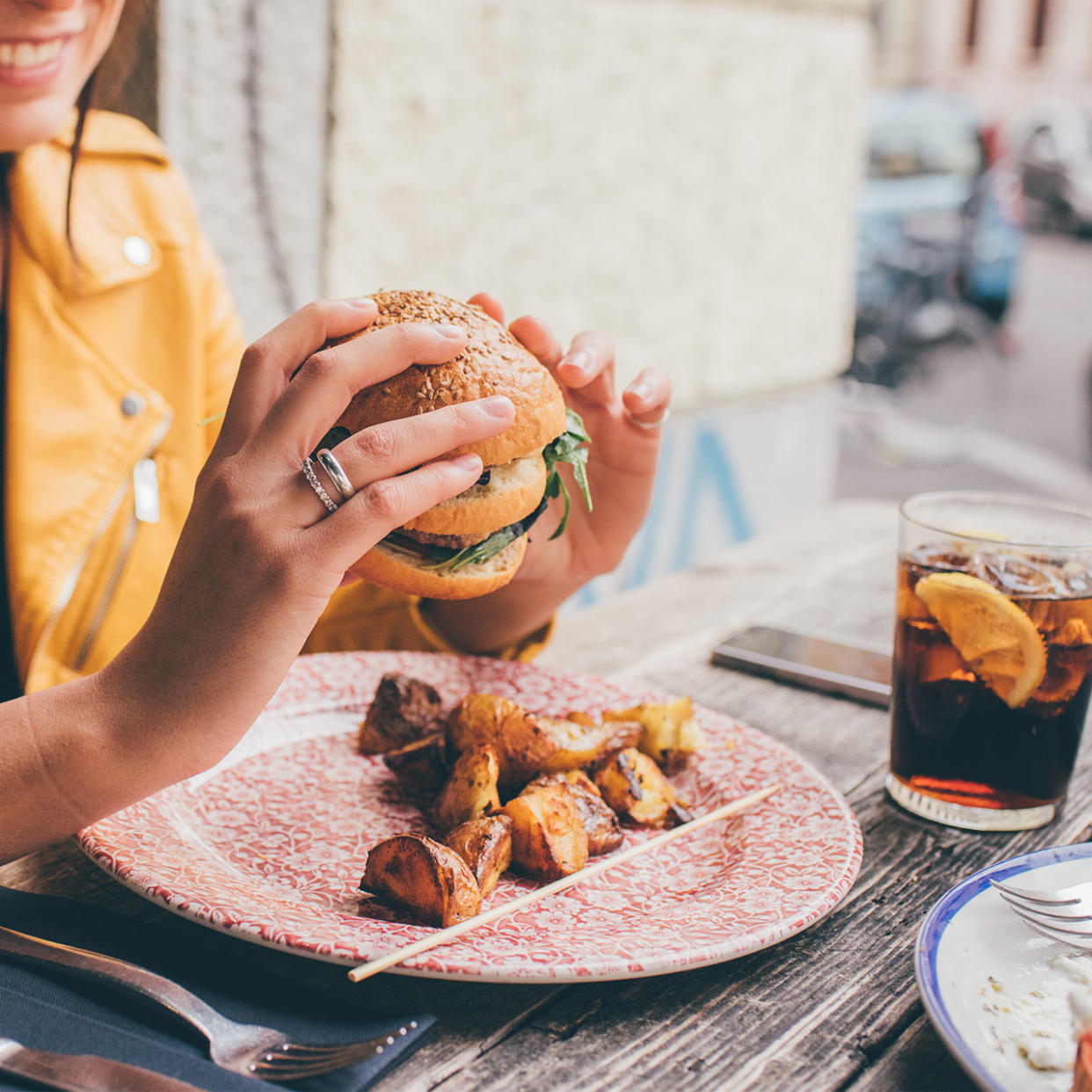 woman eating a burger with potatoes and soda