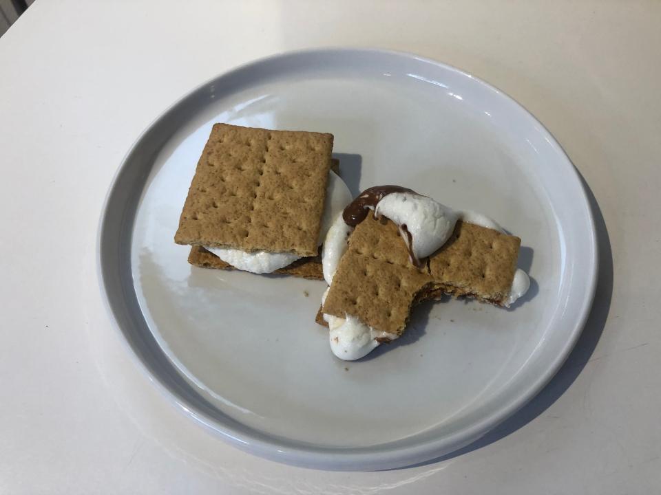 two air-fried smores, one with a bite taken out of it, on a white plate