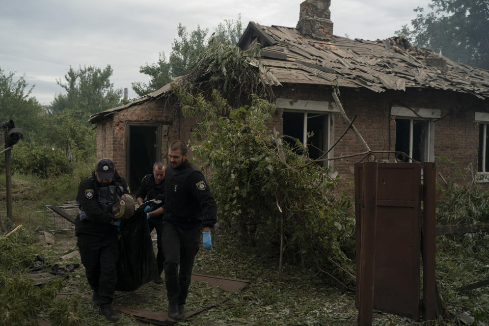 Police officers carry a bag containing the body of a person killed in his house after a Russian attack in Pokrovsk region, Ukraine, Sunday, Sept. 11, 2022. (AP Photo/Leo Correa)