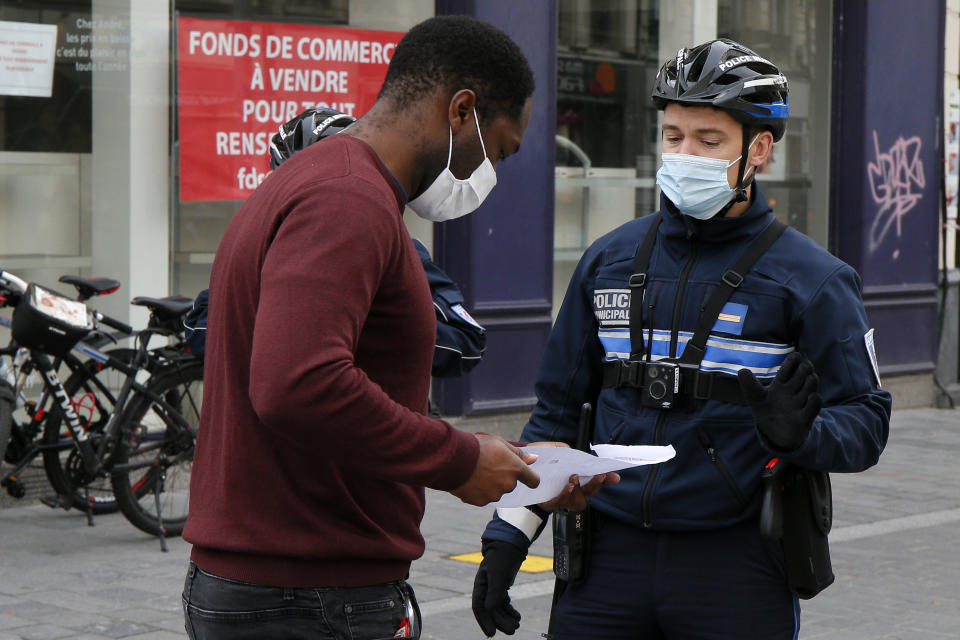 Policemen controls a resident in Lille northern France, Friday, Oct. 30, 2020. France re-imposed a monthlong nationwide lockdown Friday aimed at slowing the spread of the virus, closing all non-essential business and forbidding people from going beyond one kilometer from their homes except to go to school or a few other essential reasons. (AP Photo/Michel Spingler)