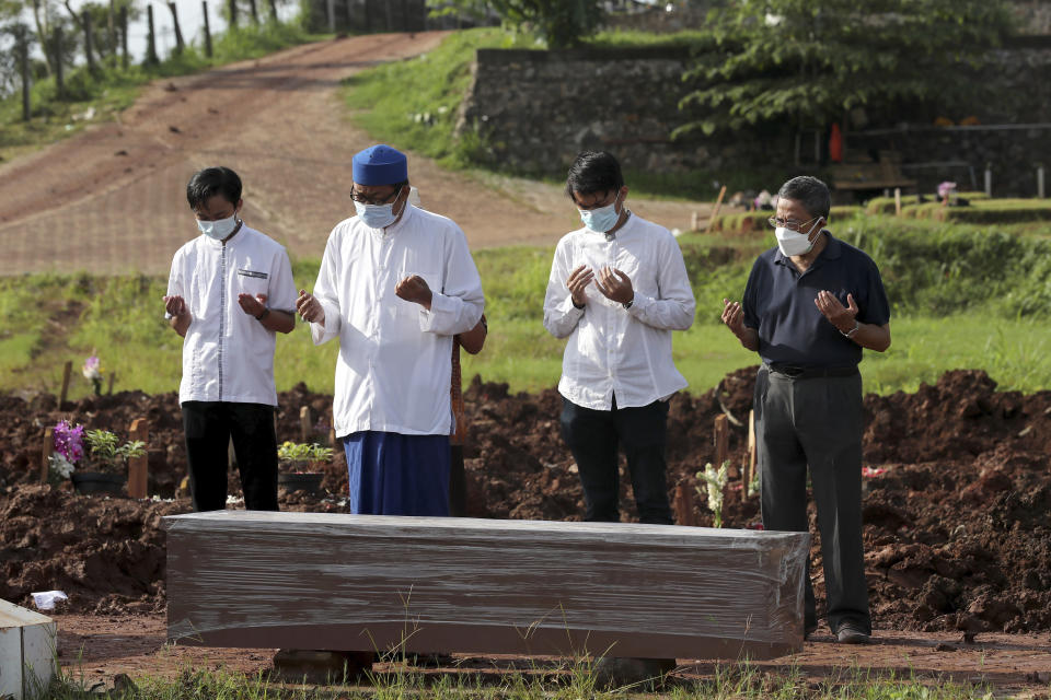 An Islamic cleric leads relatives in prayer during the burial of a man in the special section of Jombang Public Cemetery reserved for those who died of COVID-19, in Tangerang on the outskirts of Jakarta, Indonesia, Monday, June 21, 2021. Indonesia saw significant spikes in confirmed COVID-19 cases recently, an increase blamed on travel during last month's Eid al-Fitr holiday as well as the arrival of new virus variants, such as the the Delta version first found in India. (AP Photo/Tatan Syuflana)