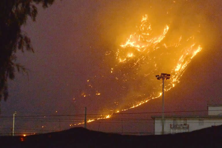 Esta foto obtenida de la agencia de noticias italiana Ansa muestra un vasto incendio que se extiende por las colinas de la zona de Monte Grifone y la localidad de Ciaculli, en los alrededores de Palermo, Sicilia, el 25 de julio de 2023, con las llamas amenazando las casas cercanas.