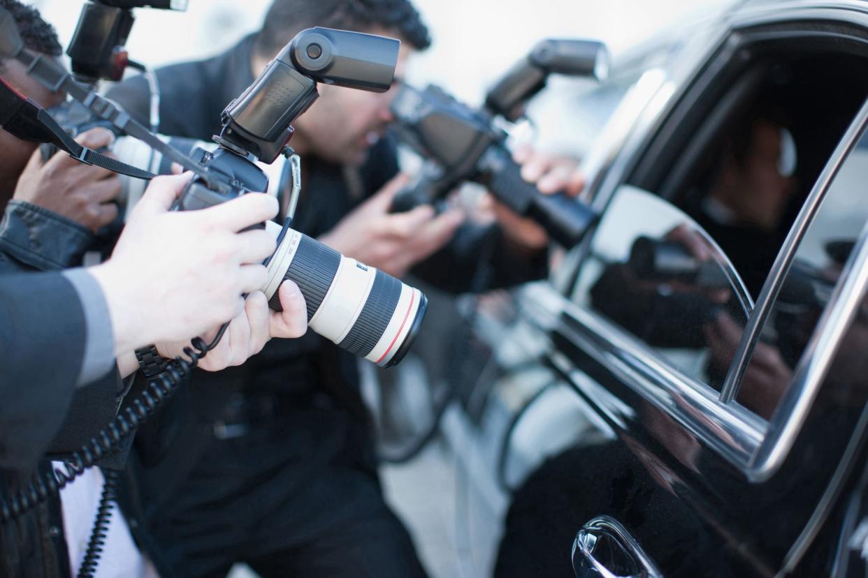 paparazzi holding camera lens to car window