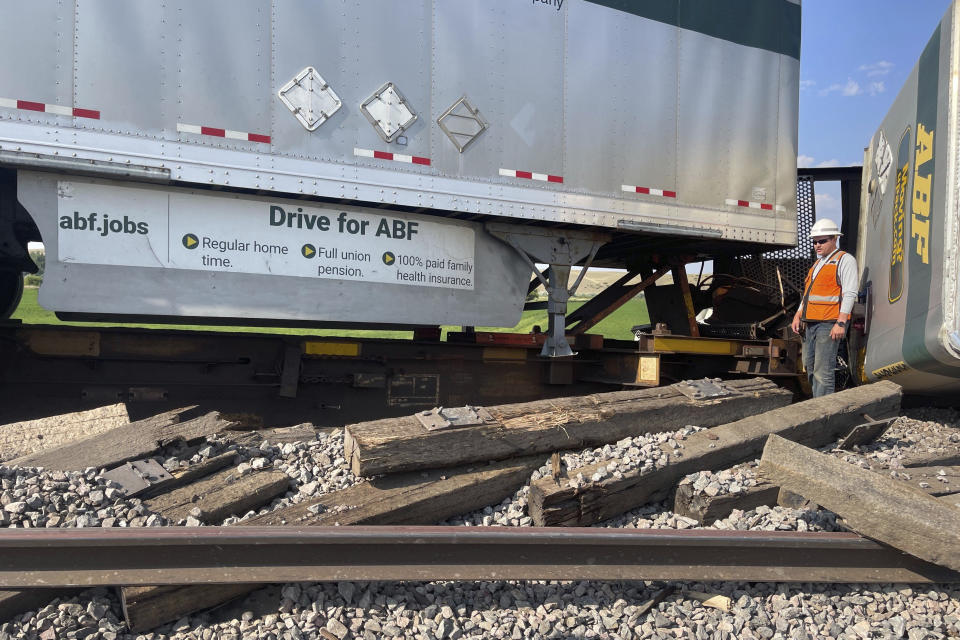 In this photo provided by Hill County Disaster and Emergency Services, a railroad worker stands among derailed freight cars from a BNSF Railway train that derailed east of Havre, Montana on Friday, July 21, 2023. Local officials said 25 cars derailed but no one was injured. The cause is under investigation. (Amanda Frickel/Hill County Disaster and Emergency Services via AP)