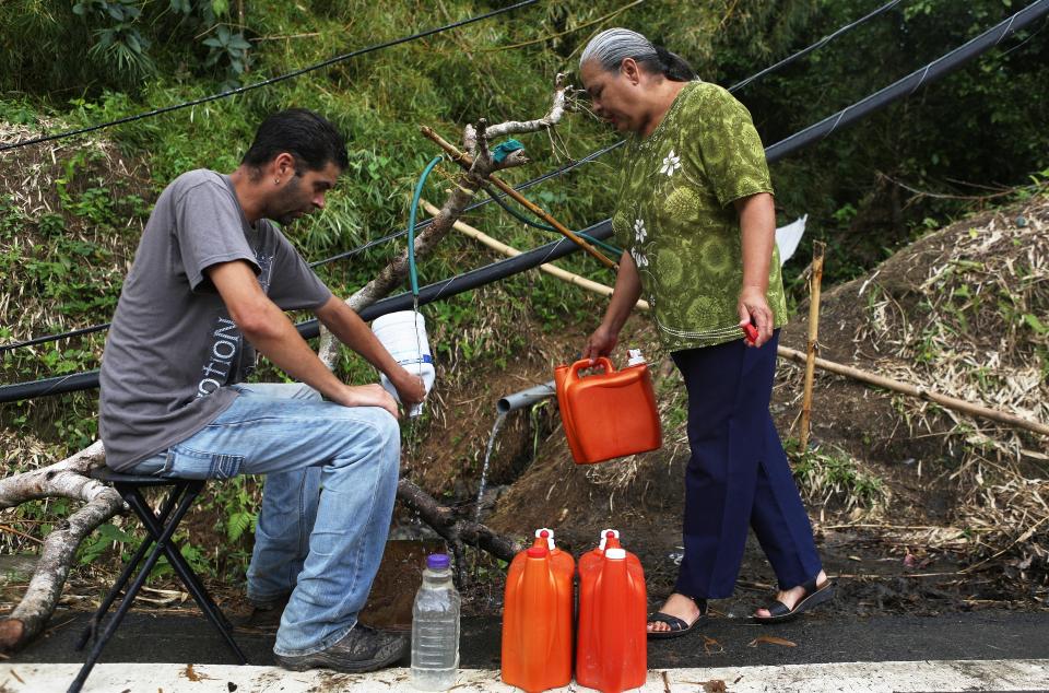 Migdalia Aceuedo and her son collect spring water in Utuado near a downed power line. Their house and much of the town is without running water or power. (Photo: Mario Tama via Getty Images)