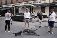 Dogs greet each other another nose-to-nose while people gather on a street in the Hell's Kitchen neighborhood of New York, Friday, May 29, 2020, during the coronavirus pandemic. The New York City immortalized in song and scene has been swapped out for the last few months with the virus version. In all the unknowing of what the future holds, there’s faith in that other quintessential facet of New York City: that the city will adapt. (AP Photo/Mark Lennihan)