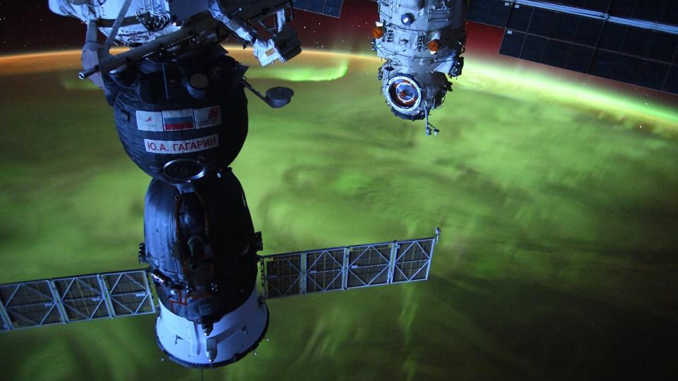 A photo of a green aurora covering the earth as viewed from the International Space Station