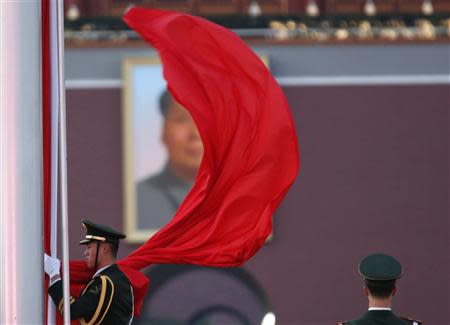 A paramilitary policeman holds the Chinese national flag at a flag lowering ceremony on Tiananmen square next to the Great Hall of the People, where the closing ceremony of the Chinese Communist Party plenum is going to be held on Tuesday, as the portrait of late Chinese Chairman Mao Zedong is seen in the background in Beijing, November 11, 2013. REUTERS/Kim Kyung-Hoon