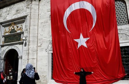 A woman poses in front of a huge Turkish flag in Istanbul, Turkey, April 13, 2017. REUTERS/Murad Sezer