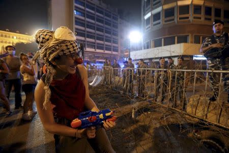 A protester wearing a red nose sprays Lebanese security members with a water gun during a protest against perceived government failures, including a rubbish disposal crisis, near the government palace in downtown Beirut, Lebanon September 9, 2015. REUTERS/Hasan Shaaban