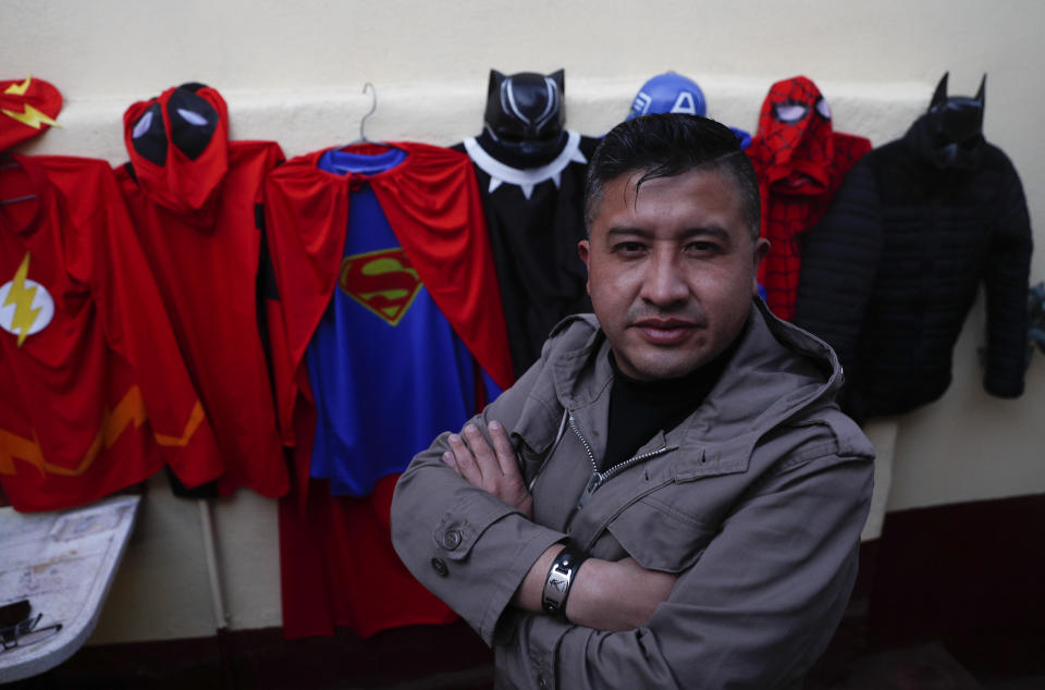 Art teacher Jorge Manolo Villarroel poses for a photo next to his superhero costumes, after imparting one of his online classes from his home, amid the new coronavirus pandemic in La Paz, Bolivia, Tuesday, June 10, 2020. Villarroel makes the costumes he wears. "I had to improvise since with the quarantine I couldn't get out," he said. (AP Photo/Juan Karita)