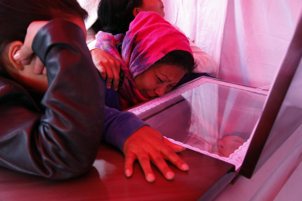 In this Jan. 11, 2019 photo, Santos Isabel Escobar weeps beside the coffin of her son, Eddy Fernando Cabrera, 18, during his wake in the same street where he was executed the night before along with four other young people in the Villanueva neighborhood of Tegucigalpa, Honduras. A bleak combination of powerful drivers like poverty and gang violence leads many Hondurans to see emigration as the only possibility for a decent life.(AP Photo/Fernando Antonio)