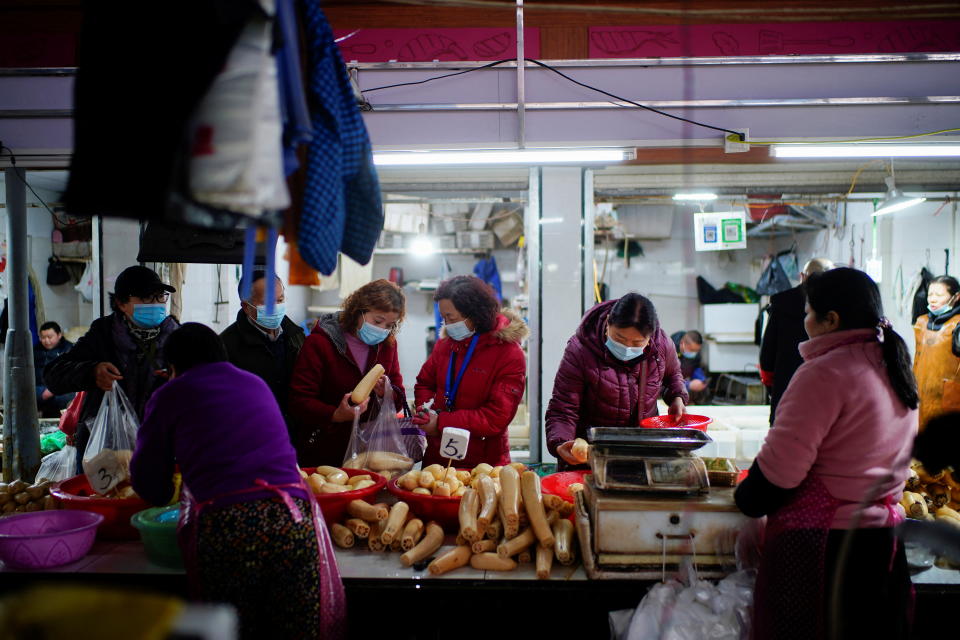 People wearing face masks buy lotus roots at a wet market, following an outbreak of COVID-19 in Wuhan, China, on Feb. 8, 2021. 