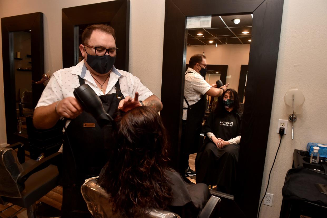 In this 2021 file photo, Salon Passion owner Enrique Ramirez styles the hair of Leslie Kaplan. Four years ago this week, Ramirez and other business owners were told to shut down in the county's Stay Well At Home order.