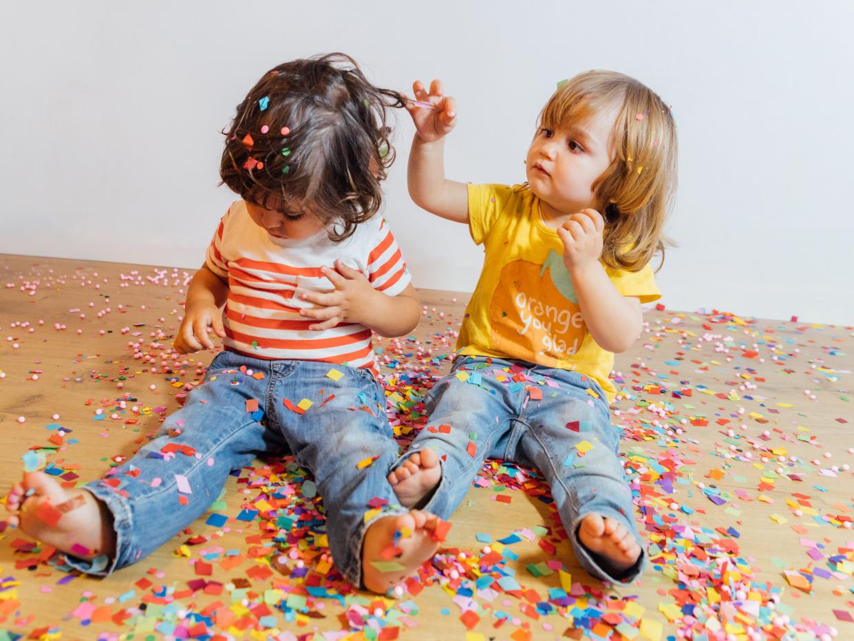 Childrens sitting on the floor playing with confetti in a playroom