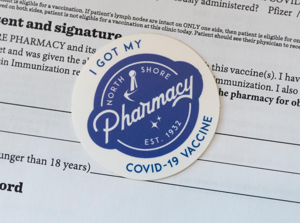 A promotional COVID vaccination sticker is shown on Tuesday at North Shore Pharmacy in Shorewood. The independently-owned pharmacy is a rarity in an era of large chains such as Walgreens, CVS and Rite Aid.