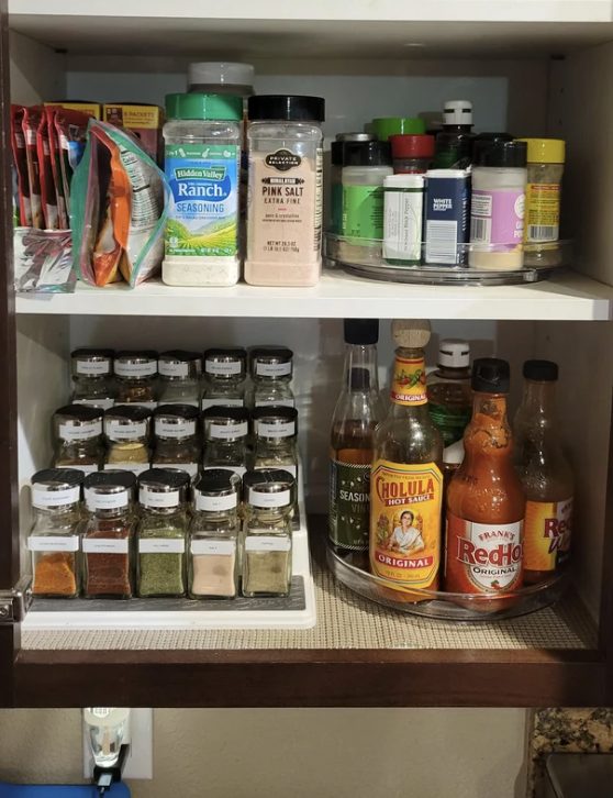 Someone's spice cabinet featuring two spice racks and a sauce rack