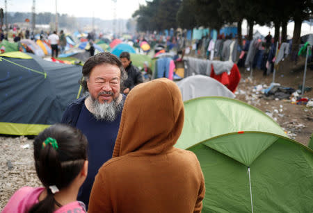 Chinese dissident artist Ai Weiwei talks with migrants in a makeshift camp on the Greek-Macedonian border, near the village of Idomeni, Greece March 11, 2016. REUTERS/Stoyan Nenov/File Photo