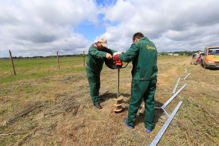 Workers drill a hole for a fence near the Sudargas border crossing point with Russia in Ramoniskiai, Lithuania June 5, 2017. REUTERS/Ints Kalnins