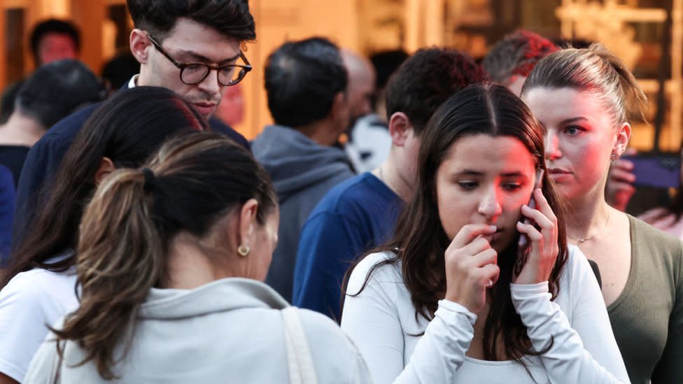 People speak on the phone at the scene outside the Westfield mall in Bondi