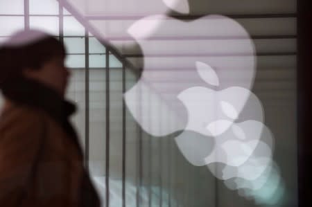 Apple company logos are reflected on the glass window outside an Apple store in Shanghai