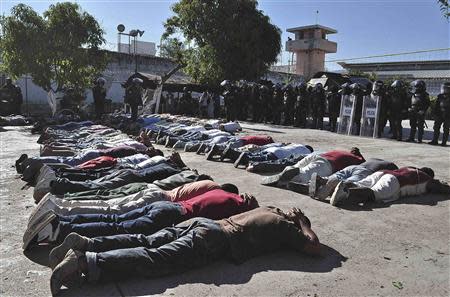 Inmates lie on the ground as riot policemen keep watch during an operation after a gunfight at the Tuxpan prison in Iguala, in the Mexican State of Guerrero January 3, 2014. REUTERS/Jesus Solano