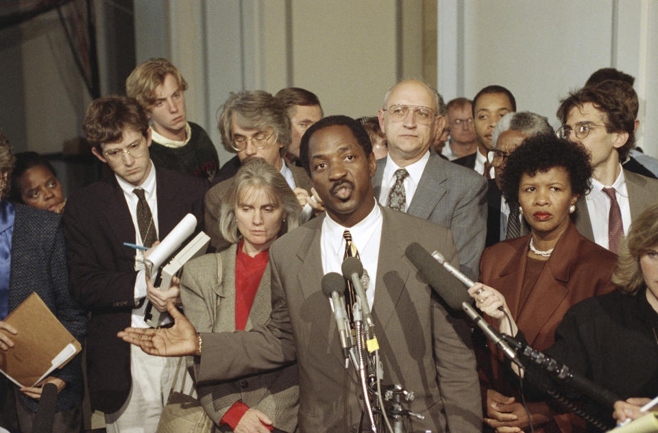 FILE - Charles Ogletree, lawyer for Anita Hill, speaks to reporters as Paul Minor, behind, looks outside the Caucus Room in the Russell Senate Office Building on Capitol Hill in Washington, Sunday, Oct. 13, 1991. Ogletree, a law professor and civil rights scholar with a distinguished career at Harvard Law School and whose list of clients ranged from Anita Hill to Tupac Shakur, died Friday, Aug. 4, 2023, after a lengthy battle with Alzheimer's disease. He was 70. (AP Photo/John Duricka, File)