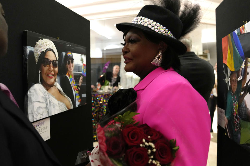 Tiffany Arieagus, a transgender woman, stands next to a photograph of herself after receiving an award at the opening reception of "Take PRIDE! A Retrospective of LGBTQ+ Life in South Florida" exhibit, Wednesday, May 31, 2023, in Fort Lauderdale, Fla. Arieagus, 71, an acclaimed drag performer in south Florida, also works in social services for SunServe, an LGBTQ+ nonprofit. (AP Photo/Lynne Sladky)